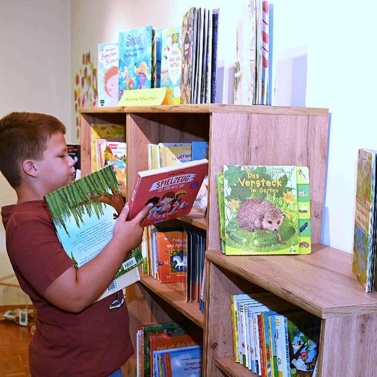 Bub mit Büchern vor einem Regal